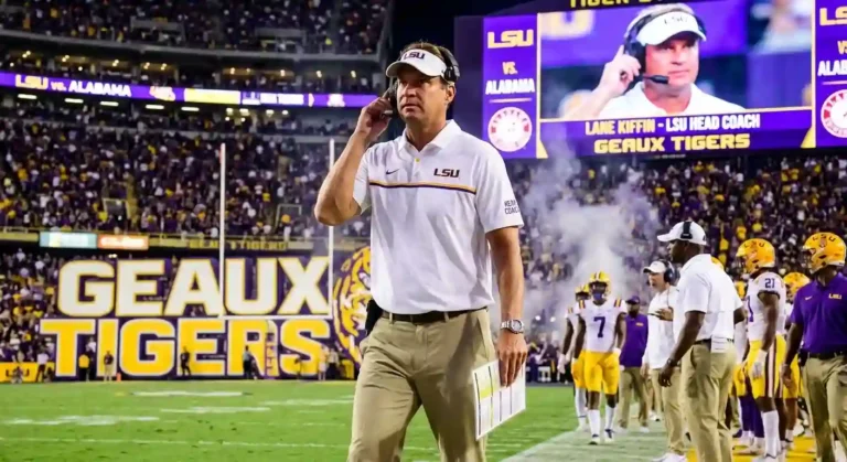 LSU Tigers football head coach walking on the sideline during a game in Death Valley stadium.