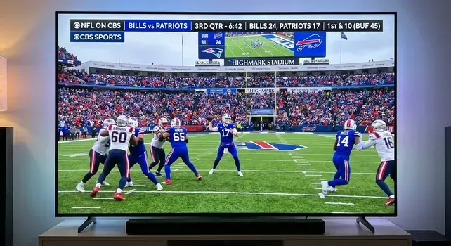 Smart TV displaying Buffalo Bills vs New England Patriots live game broadcast on CBS Sports at Highmark Stadium.